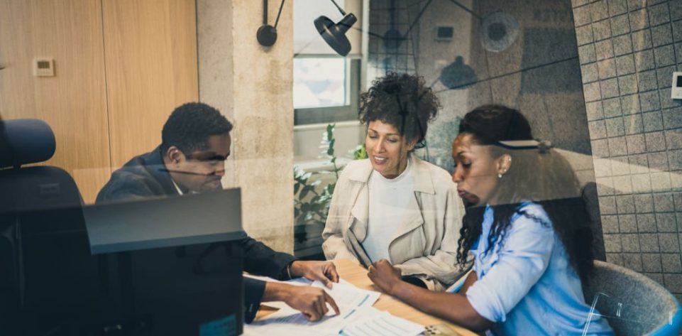 African-American financial advisor talking to female couple about investment opportunities.